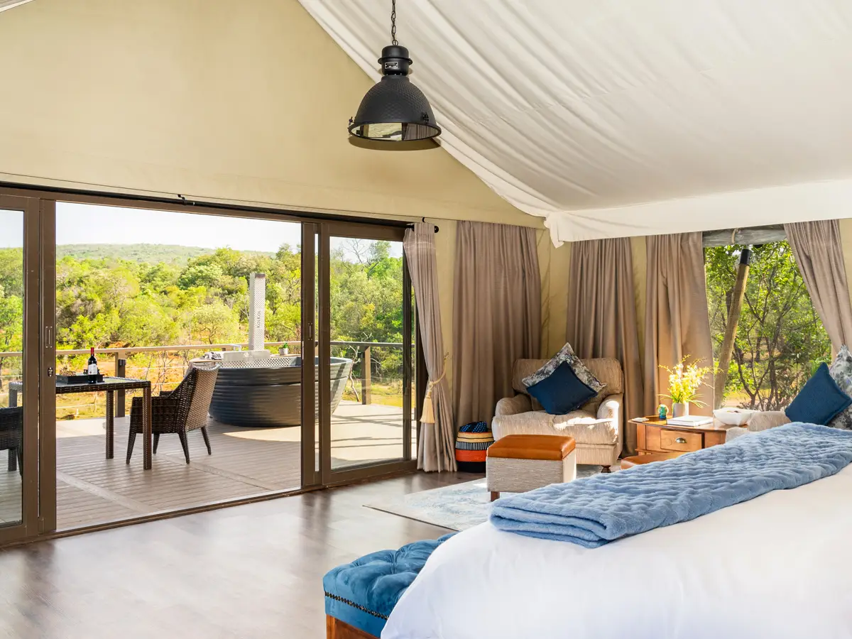 Interior of The Eland suite at Hippo Lakes: freestanding tub, four-poster bed, and a bush view