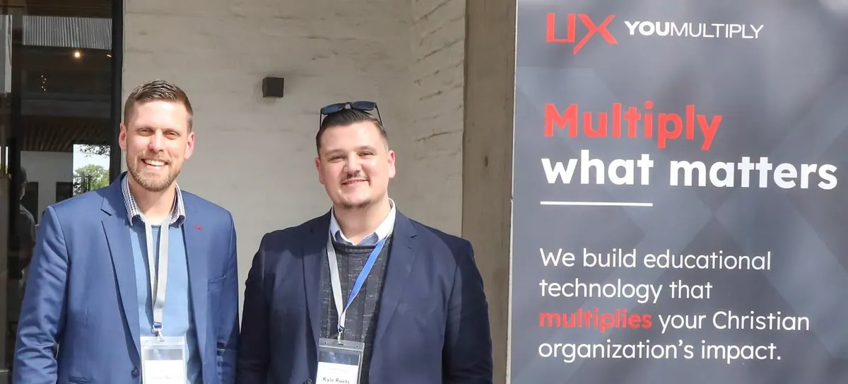 Louis Barry and Kyle Roets beside the YouMultiply banner at a theology conference